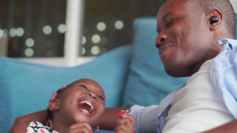 Cheerful african american father and daughter playing in living room, Cute little girl enjoying with chocolate, Happiness family concepts
