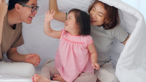 Happy family with mother, father and disabled daughter spending time together in bedroom.