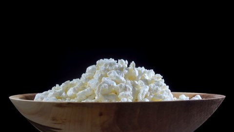 A pile of cottage cheese in a plate rotates in 4K on a black background.