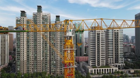 Drone aerial view of crane in construction site with building in background. House or real estate development, property building concept. Yellow crane. Busy construction site in Shanghai China.