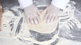 Chef stretches dough with gloved hands