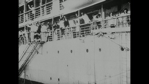 1910s: Naval officers and dock workers walk away from ship. Passengers wave from railings of steamer ship as it departs. Ships sit in bay near docks.