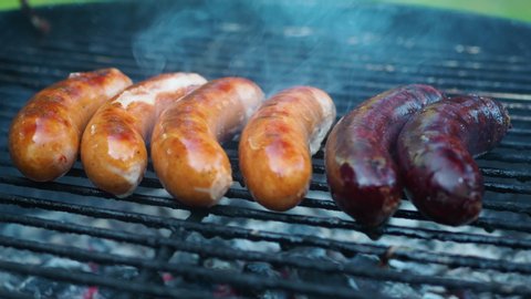 Close shot of grilled sausage on BBQ with charcoal.