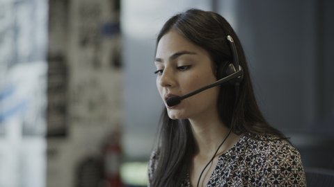Close up of serious businesswoman wearing headset talking in call center / Pleasant Grove, Utah, United States
