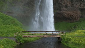 Seljalandsfoss Waterfall located on the Seljalands River in Iceland with a wooden footbridge in the foreground. 4K UHD video.