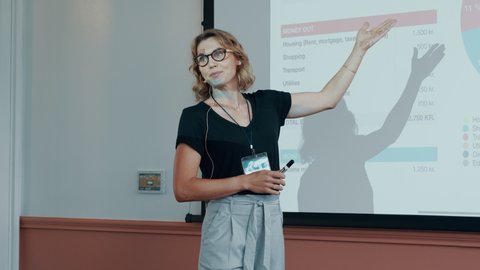 Female entrepreneur giving a presentation at a business conference. Woman making a presentation in a seminar and showing statistical graphs.
