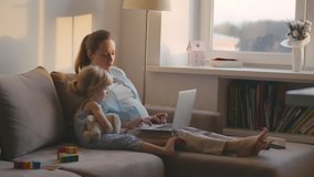 Happy pregnant mother with her little daughter using laptop at home in living room. Young woman watching cartoons on laptop with cute toddler girl staying home during epidemic danger. Self-isolation - Powered by Shutterstock - Get 15% off with code: PIKWIZARD15