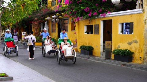 Hoi An, Vietnam - june 29, 2020 : Trishaws ride tourists on a tricycle down the street in Hoi An Old Town, Vietnam. Trishaws are very popular with tourists, as traffic in city on cars is prohibited 