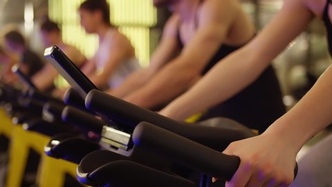 Group of athletic young people stationary bicycle doing spinning at gym . A group of young women and men train on sports training equipment in a fitness gym . Healthy Lifestyle and Sport Concepts