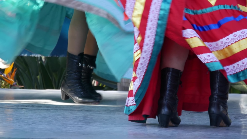Latino women in colourful traditional dresses dancing Jarabe tapatio, mexican national folk hat dance. Street performance of female hispanic ballet in multi colored ethnic skirts. Girls in costumes. | Shutterstock HD Video #1058035255