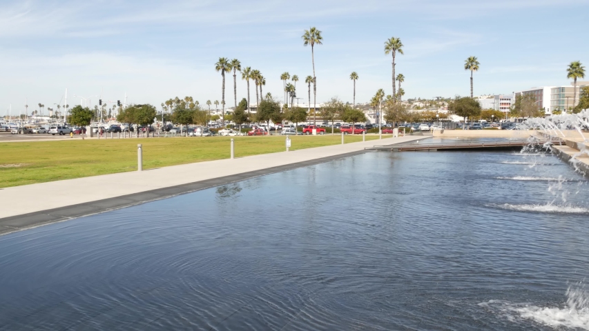 Fountain in waterfront city park near San Diego county civic center in downtown, California government authority, USA. Pacific ocean harbour, embarcadero in Gaslamp Quarter. Palms and grass near pier.