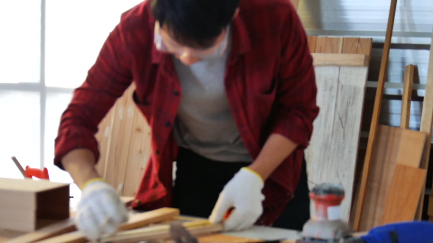 young Asian man wearing protective white  gloves working DIY home improvement the wood plank in the workshop working at home