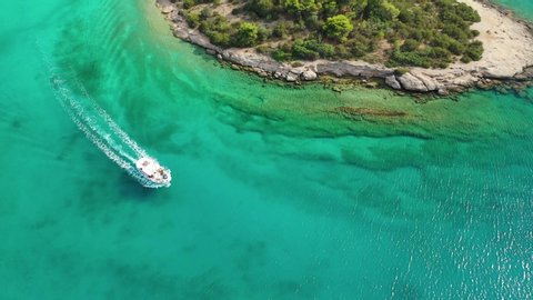 Aerial drone video of small boat cruising in Caribbean tropical rocky bay with turquoise - crystal clear sea