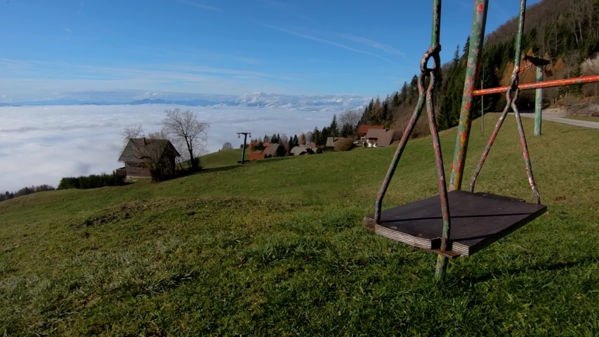 Left truck moving kids swing equipment on hilltop with view on village and low altitude fog