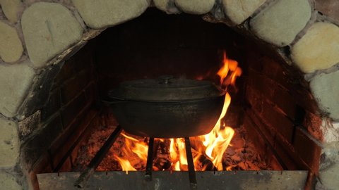 Cooking on fire wood burning in the oven. Open air stove. Saucepan with food on an open fire. Cooking outdoor. Traditional Pizza oven. saucepan on open fire. Organic natural food cooked outdoor