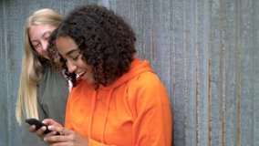 Slow motion video clip of pretty blonde girl and mixed race teenager young women taking selfies on their smart phones for social media