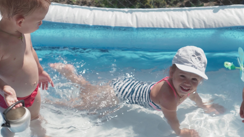two small children boy and girl Caucasian European Slavic appearance of same age are happy bathe and frolic in pool in summer, splashing water, lifestyle design. Activity nature leisure. Slow motion