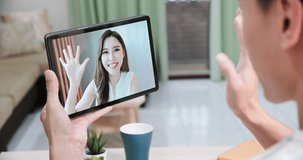 back view of asian young man has video chat with girlfriend by digital tablet in the living room at home