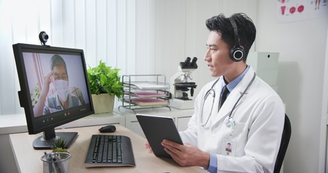 Telemedicine concept - asian young doctor is listening to elder patient and then talking about his symptom on webcam