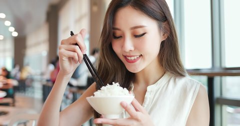 asian young woman eat rice with chopsticks in the restaurant