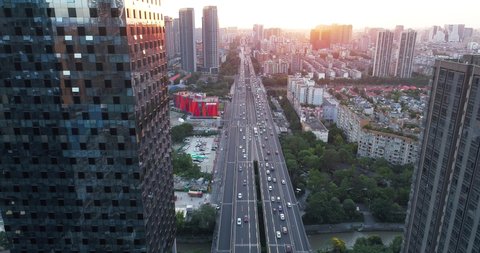 Aerial view of Chengdu Cityscape at sunset with cars driving on the 2th ring Fly over road high office buildings by the roadside 