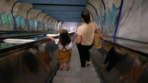 Helsinki, Finland - June 21, 2020: Mother and daughter go down by the escalator in the subway.