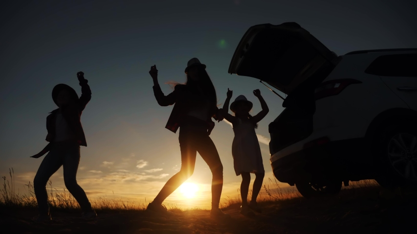 happy family kid dance picnic are jumping dancing dream holiday concept. happy family jump three girls teenagers are standing at sunset next to the car stopped at a picnic. open car lifestyle trunk Royalty-Free Stock Footage #1058068126