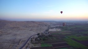 Aerial video motion riding hot air balloon over Luxor Egypt valley of the king Unesco heritage site at sunrise