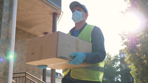 Courier wearing gloves and a mask goes to deliver food and goods during the covid coronavirus pandemic. A volunteer courier delivers online purchases. Technologies during the coronavirus pandemic