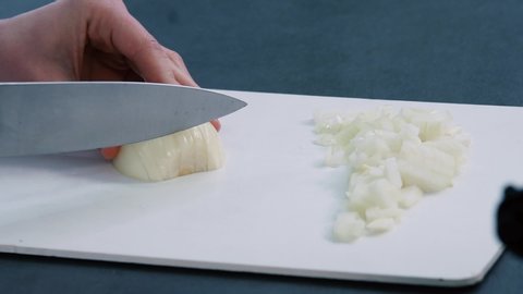 Woman use a kitchen knife to chop the onions on a cutting board. Healthy ingredient for cooking. Making food. Cutting white onions.
