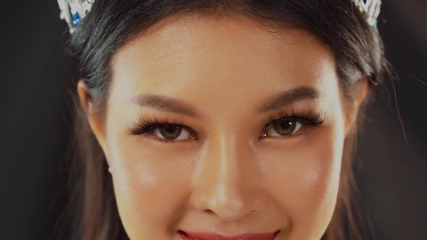 Amazing beautiful eyes with long, artificial eyelashes smiles and blinks as this Asian beauty queen poses