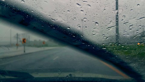 Car run through rain strom with poor visibility on highway. Hard rain drop on front window car making it difficult and dangerous to drive.
