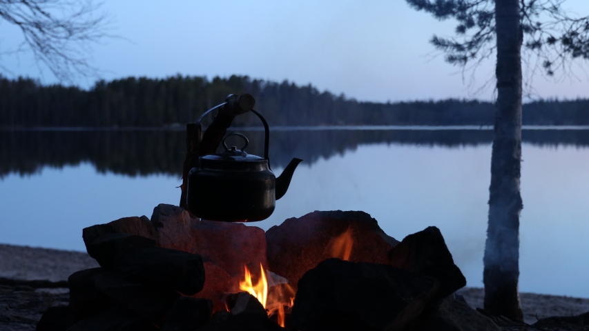 Old coffee pot on camping fire. Wonderful evening atmospheric background of campfire. The concept of adventure, travel, tourism and camping.