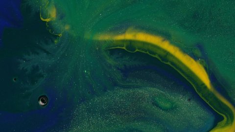 Yellow, green and blue liquid glitter paint. Abstract art background. A real beautiful substance flows. Motion mixed colorful ink