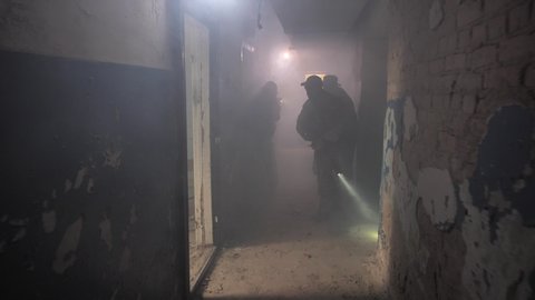 Three experienced special forces fighters throwing granade and opening fire through doorway while suspecting presence of enemy in a room of captured ruined building. Well-coordinated trio on mission