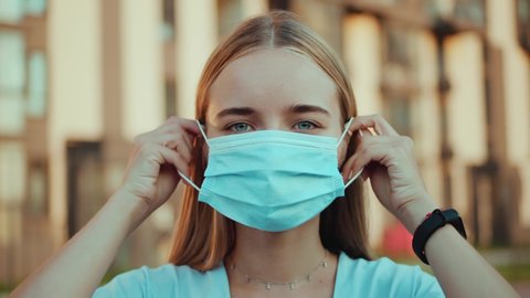Close up attractive woman wearing protective mask on street look at camera pandemic Covid-19 coronavirus quarantine safety prevention flu pollution virus health coronavirus outside slow motion