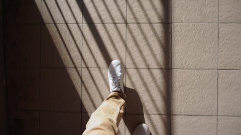 man in white sneakers walks down the street on a bright Sunny day. pov video, first person