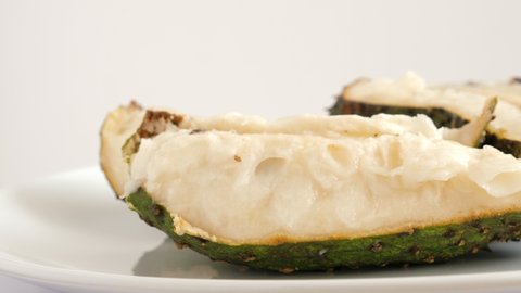 One sliced soursop graviola, exotic, tropical fruit Guanabana on plate, Rotate. Food background