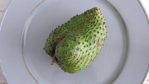 One soursop graviola, exotic, tropical fruit Guanabana on plate, Rotating. Food background