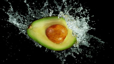 Super Slow Motion Shot of Half Avocado with Splashing Water Isolated on Black Background at 1000fps.
