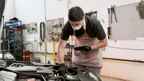Mechanic with covid mask checking car and taking notes on digital note pad - Powered by Shutterstock - Get 15% off with code: PIKWIZARD15