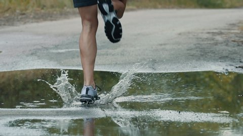 Running Man On Puddle.Runner Jog Exercising Outdoors.Runner Man Fit Athlete Legs Jogging On Puddle Ready To Triathlon.Triathlete Running,Sprinting And Endurance Marathon Workout.Sport Fitness Concept.