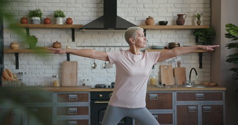 Healthy elderly senior woman doing yoga exercise at home Stockvideó