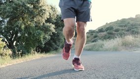 Video of athletic strong mature sportman running outside road through field.