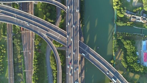 Aerial drone view of highway multi-level junction road with moving car at sunset. Active movement of transport cars vehicles in different directions. China. Top down view, rotation shot.