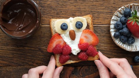 Time lapse preparing kids food, food art of funny cute owl toast with chocolate nut spread, soft white cheese and berries. School lunch box or bento box concept