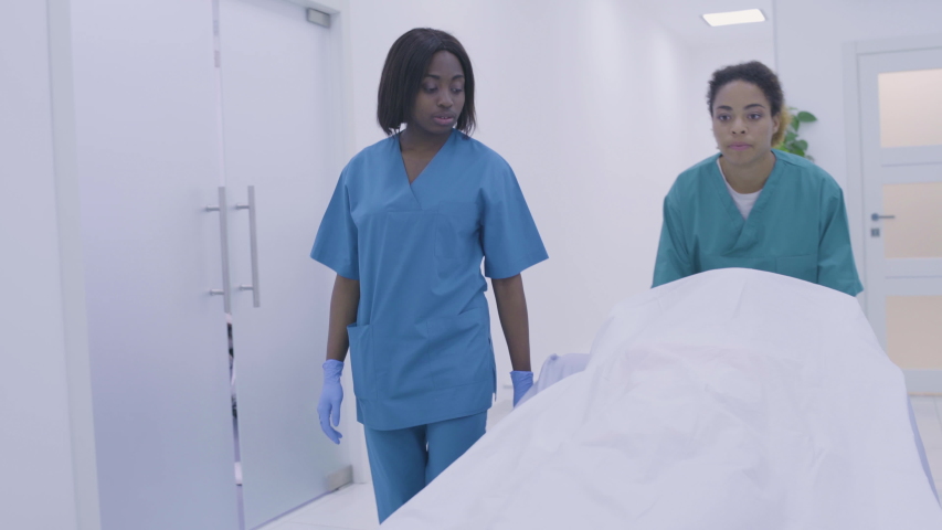 Black medical workers pushing wheel bed down hospital hall, death of patient Royalty-Free Stock Footage #1058122033