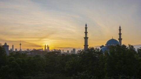 Time lapse. Sunrise at a mosque with silhouette Kuala Lumpur city skyline in the background from afar. KL, Malaysia. Prores Full HD