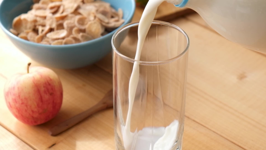 Slow motion Pouring milk in glass on wooden table. Healthy breakfast at the morning. Cereals and milk Royalty-Free Stock Footage #1058122864