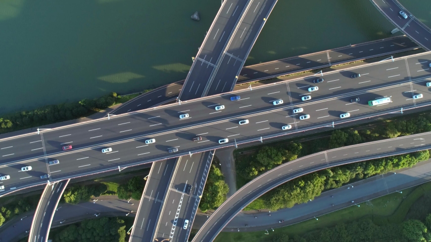 Aerial drone view of highway multi-level junction road with moving car at sunset. Active movement of transport cars vehicles in different directions. China. Top down view, rotation shot.